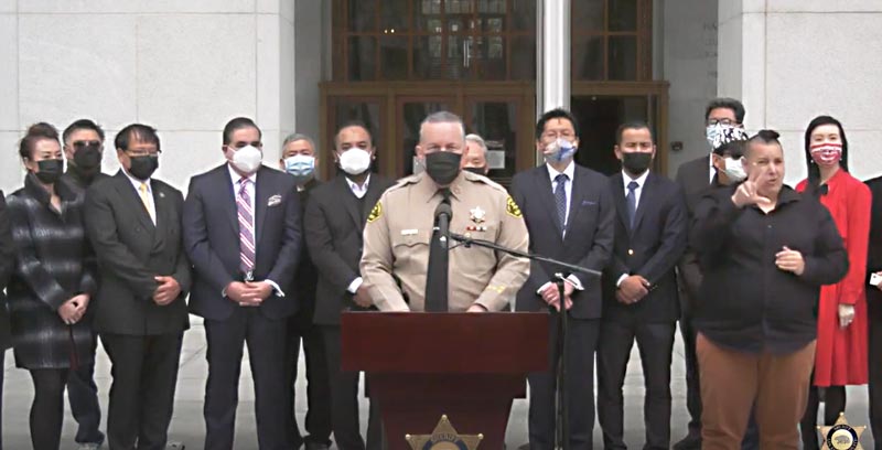 Sheriff Villanueva speaking at a podium surrounded by Consulates from the Asian and Pacific Island nations of LA County
