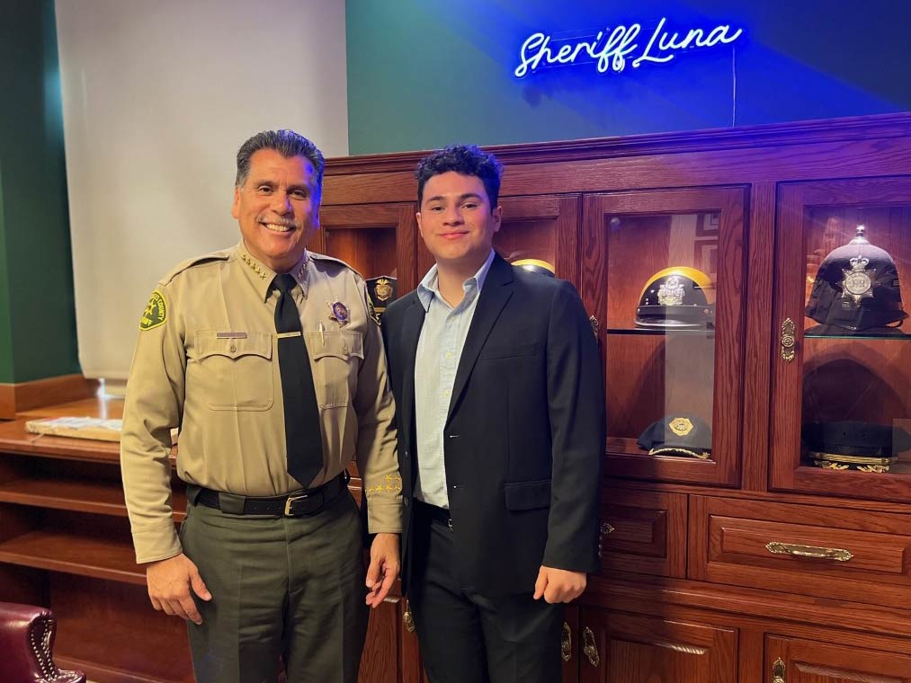 Luis standing next to sheriff luna. Luna is in uniform.