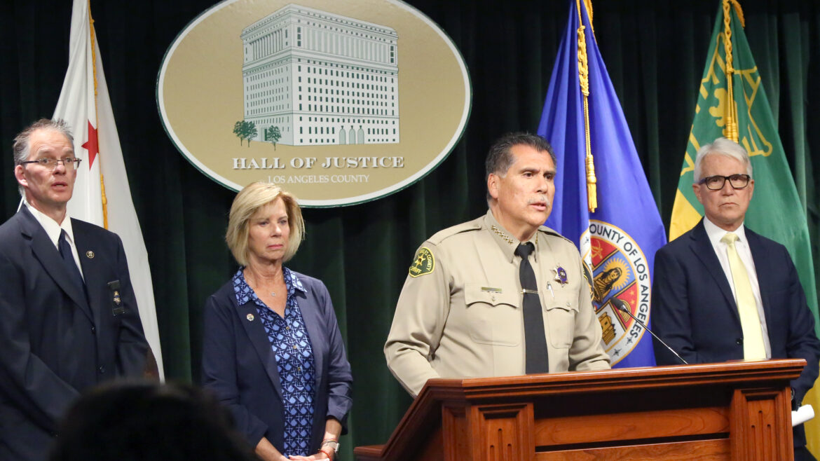 Sheriff Luna at a poduim with District Attorney Gascon, and Supervisor Janice Hanh in the background