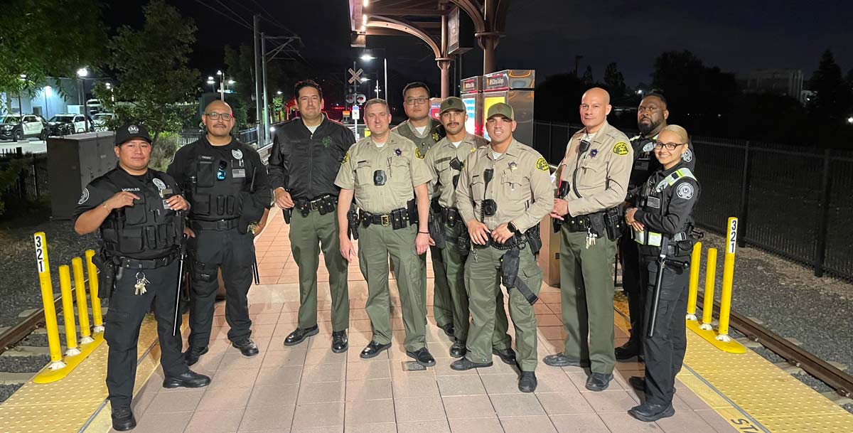 Group of Deptuies pose for pictures with Metro Security on metro platform.