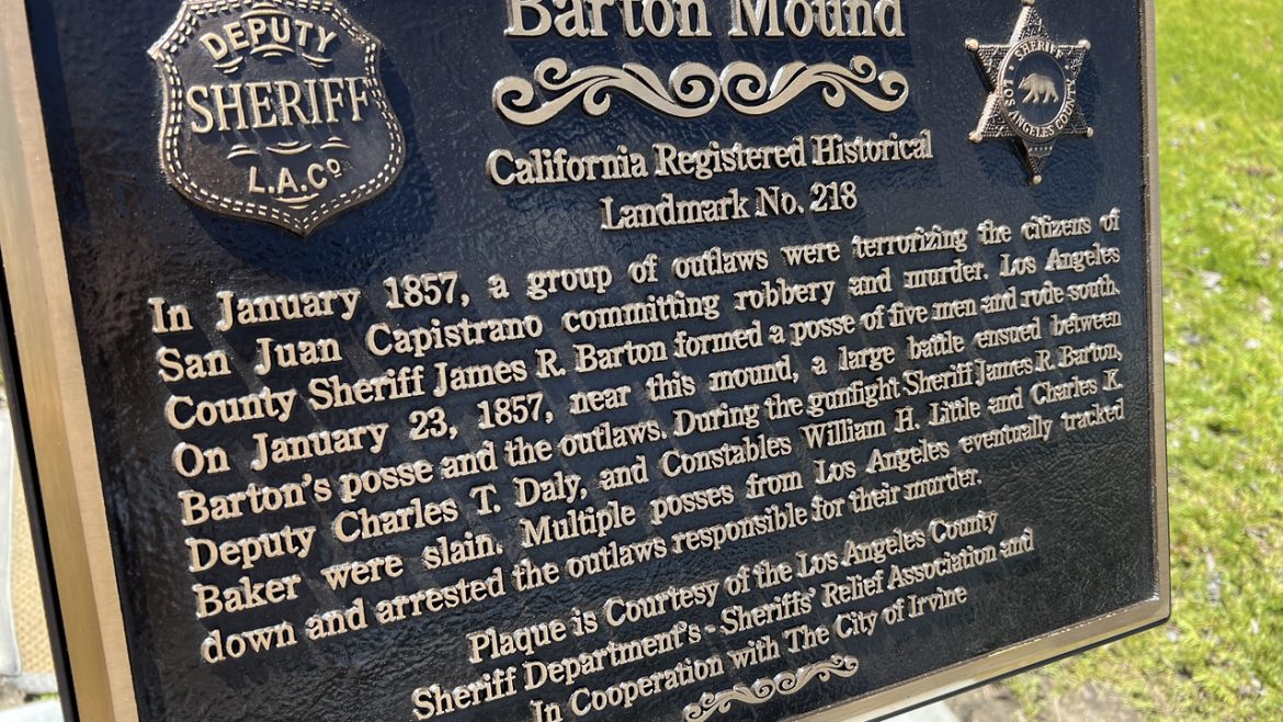 image of memorial plaque. Black background and gold letters. relief of old sheriffs badge on left and modern badge on right. Barton mound - California Registered Historical Landmark No. 218. In January 1857, a group of outlaws were terrorizing the citizens of San Juan Capistrano committing robbery and murder.